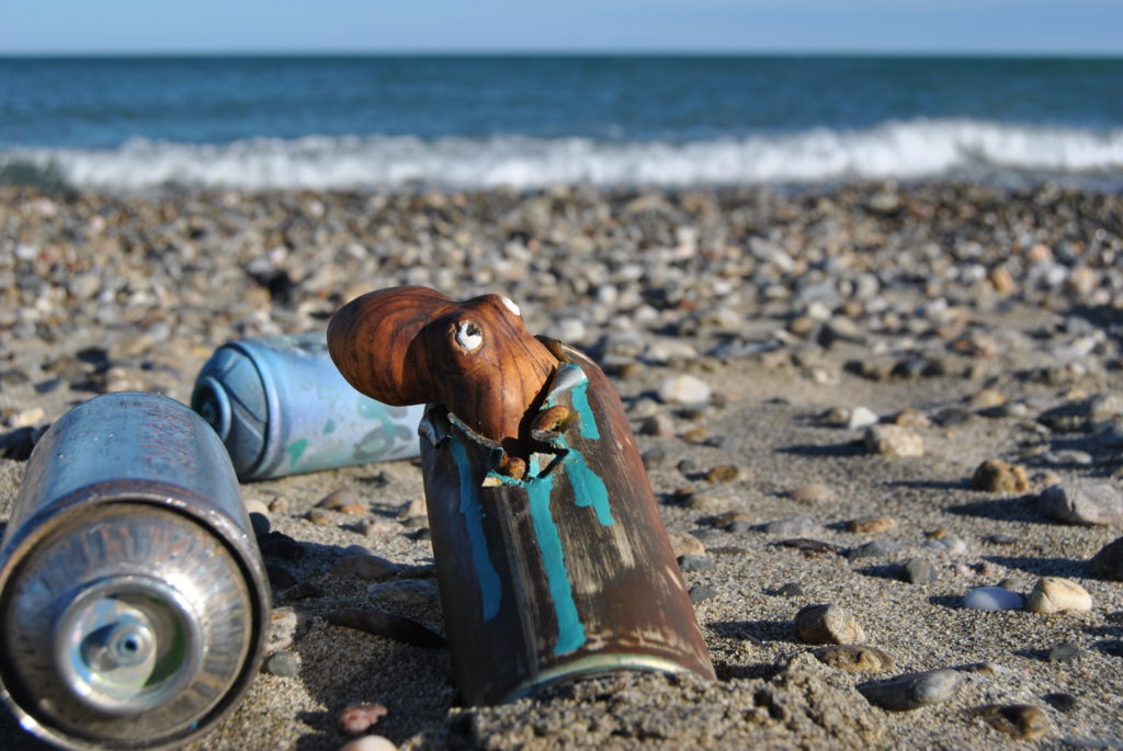 Bombe de peinture avec une sculpture de pieuvre posé sur la plage